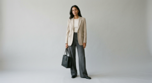 A minimalist, editorial-style photograph featuring a woman in a neutral-toned, sleek outfit against